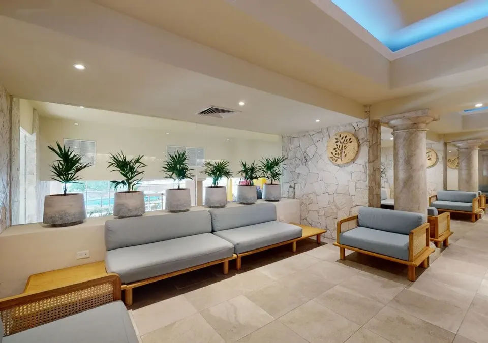 Indoor seating lounge with plants and stone columns at Grand Park Royal Cancun.