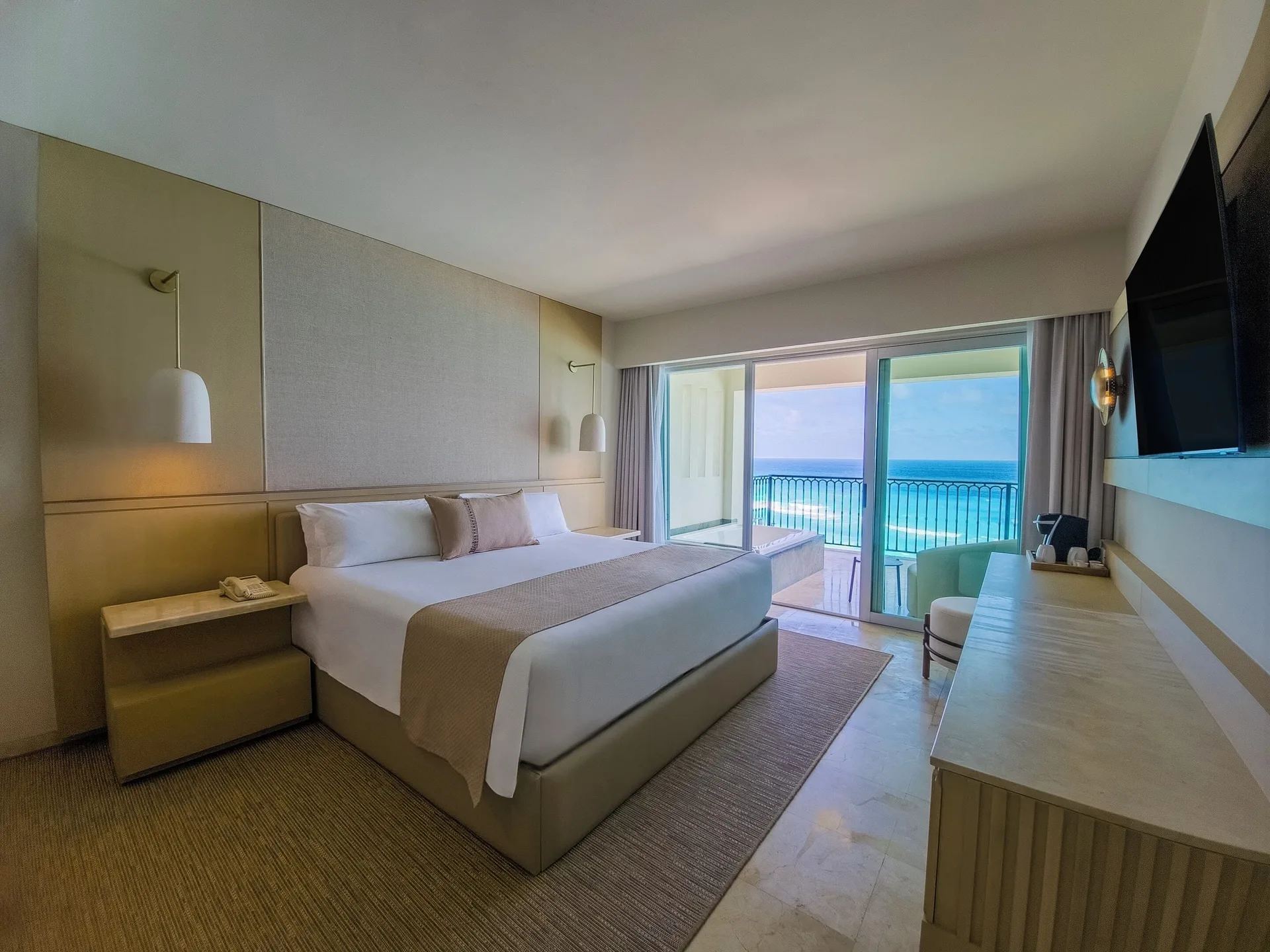 King bed guest room with open balcony doors at Grand Park Royal Cancun.
