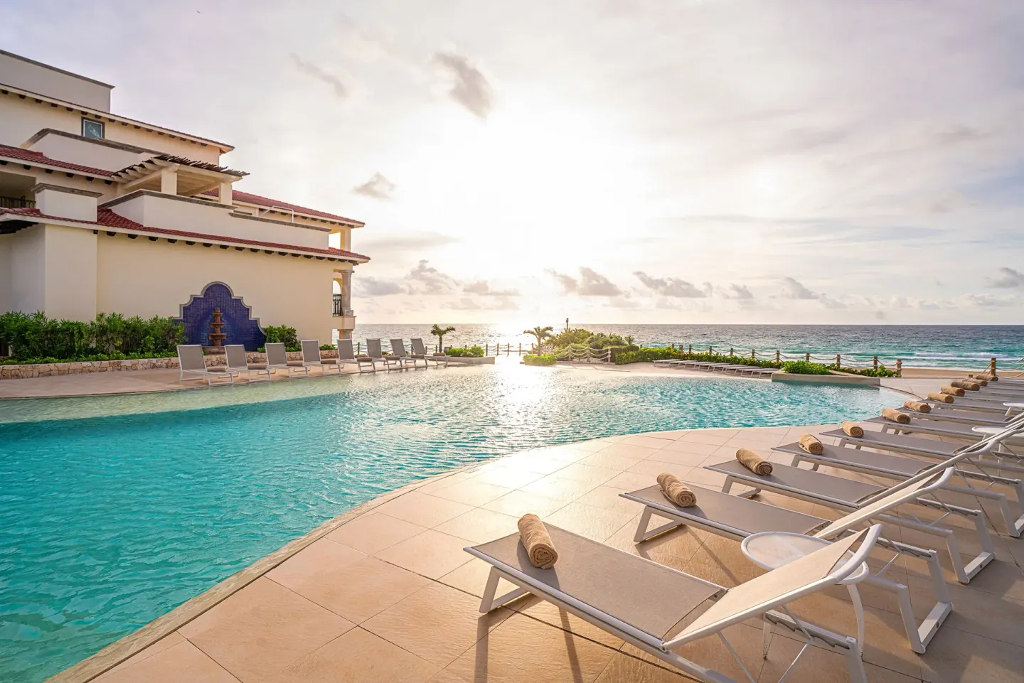 Oceanfront pool with loungers and sunset at Grand Park Royal Cancun.