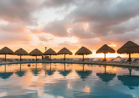 Resort pool with palapas and loungers at sunset at Grand Park Royal Cancun.