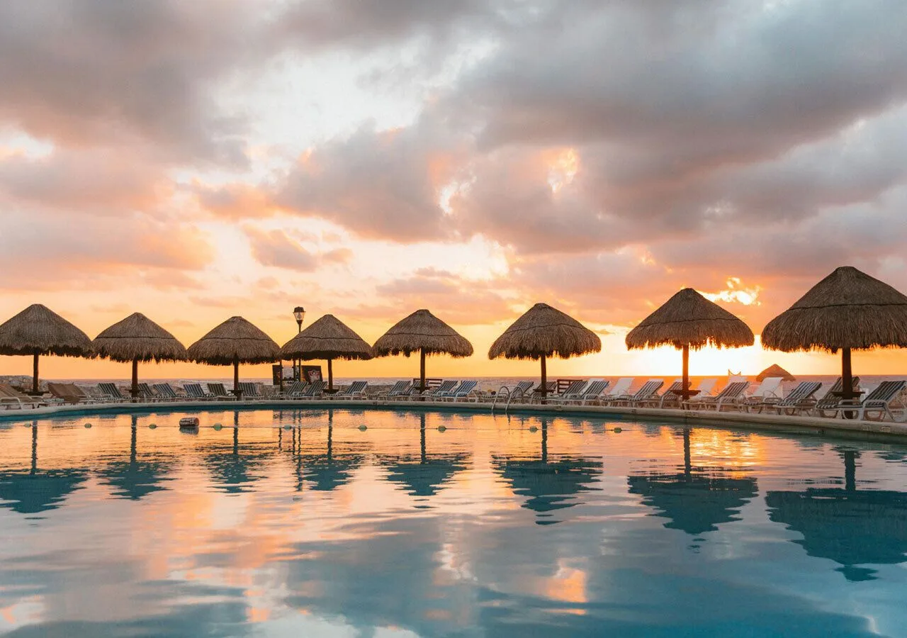Resort pool with palapas and loungers at sunset at Grand Park Royal Cancun.