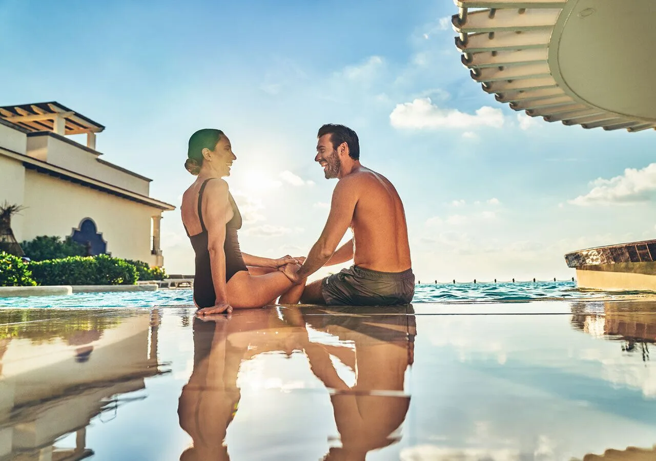 Couple sitting at the pool edge at Grand Park Royal Cancun.