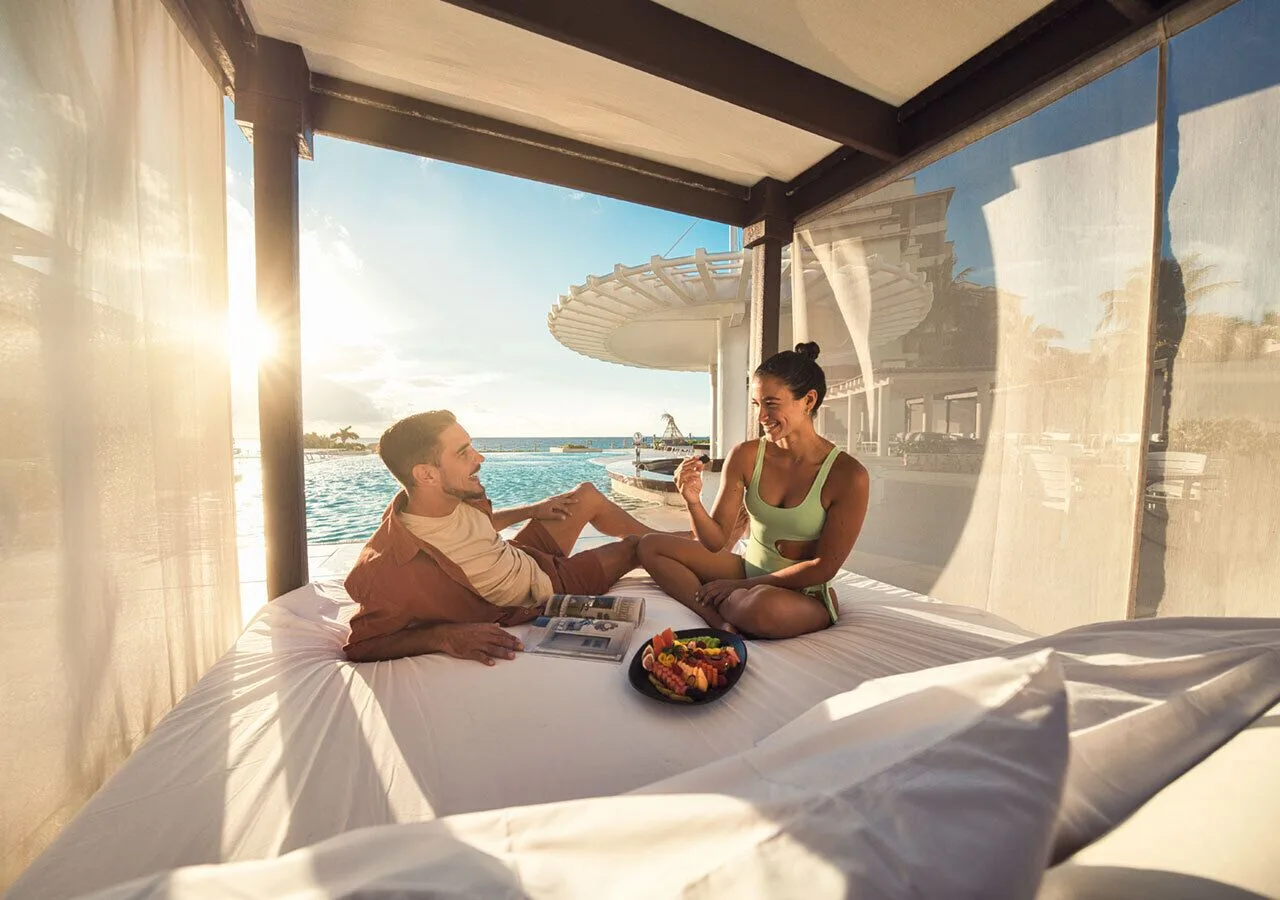 Couple relaxing on a poolside daybed at Grand Park Royal Cancun.