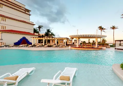 Pool with in-water loungers and resort buildings at Grand Park Royal Cancun.