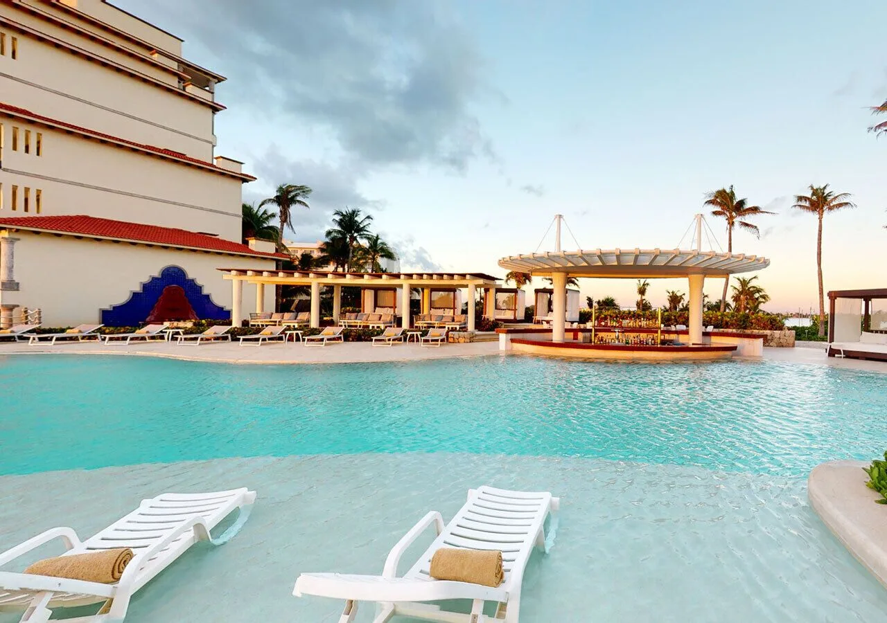 Pool with in-water loungers and resort buildings at Grand Park Royal Cancun.