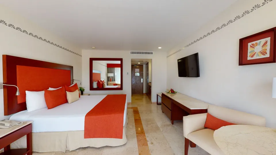 Deluxe Swim Up king room with sofa and wall-mounted TV at Grand Park Royal Cancun.