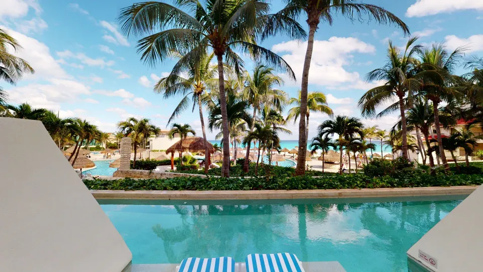 Deluxe Swim Up terrace view of pool, palms, and ocean at Grand Park Royal Cancun.