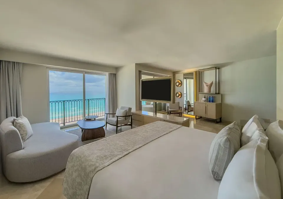 Royal Master Suite king bed with sofa, TV, and ocean view at Grand Park Royal Cancun.