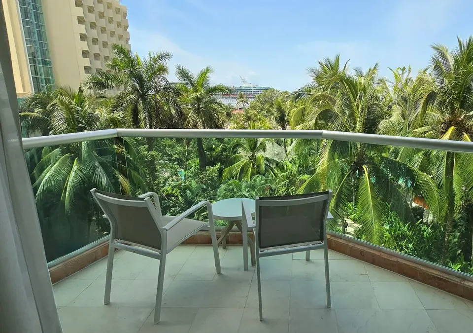 Balcony with two chairs and table looking over lush palms at Grand Park Royal Cozumel