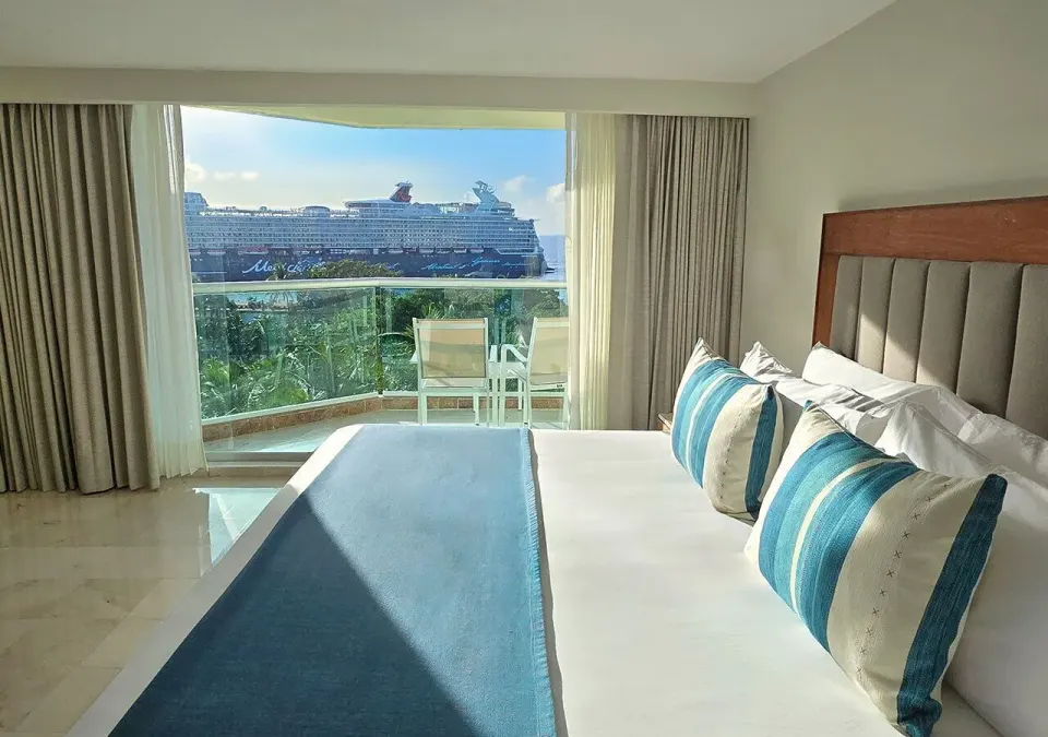 King bed with balcony and cruise ship visible offshore at Grand Park Royal Cozumel