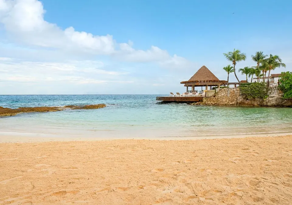 Quiet sandy beach with palapa and calm water at Grand Park Royal Cozumel