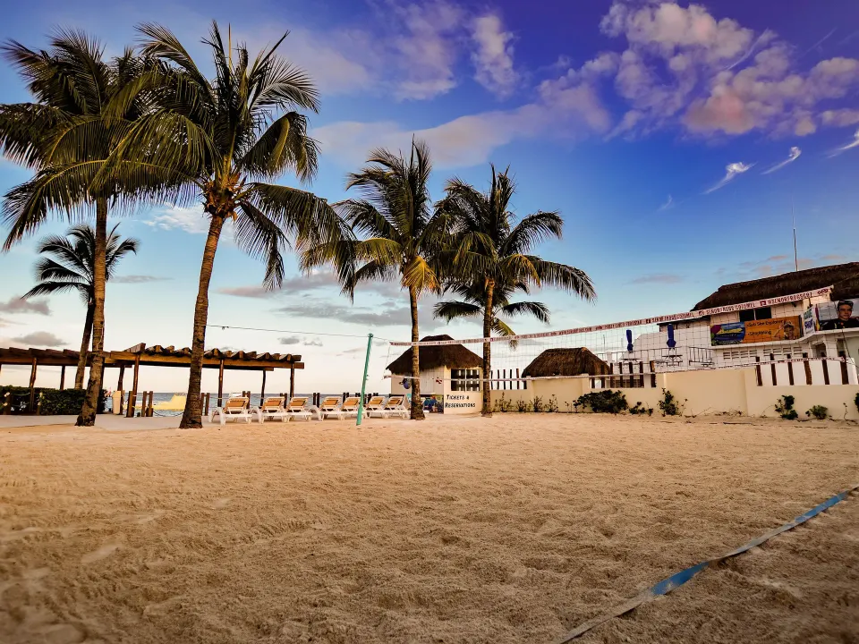 Sandy beach with palm trees, volleyball net and beachfront seating at Grand Park Royal Cozumel
