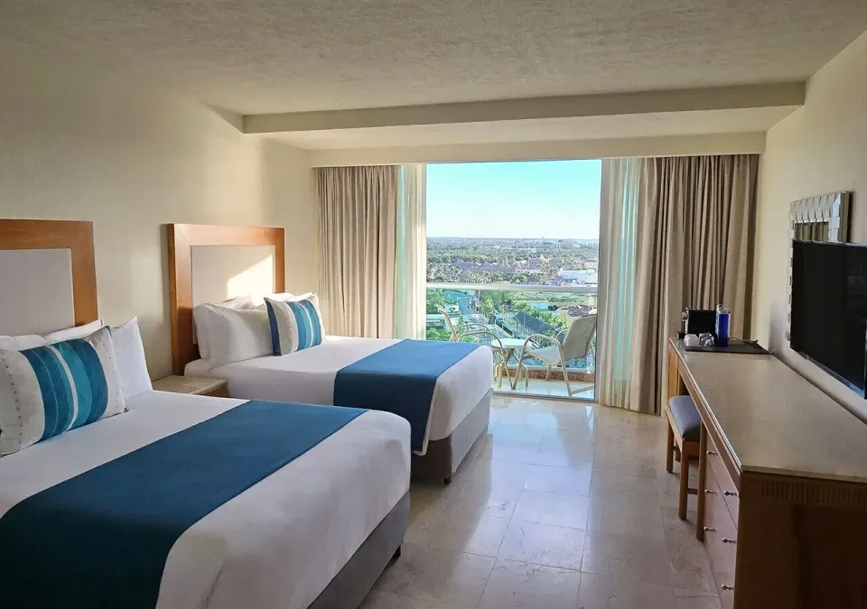 Two double beds and balcony with distant coastline visible at Grand Park Royal Cozumel