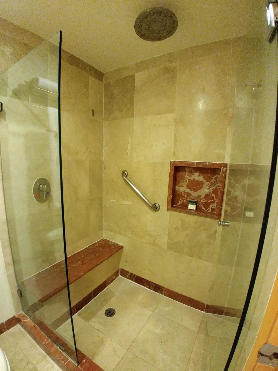 Walk-in tiled shower with bench and glass door at Grand Park Royal Cozumel
