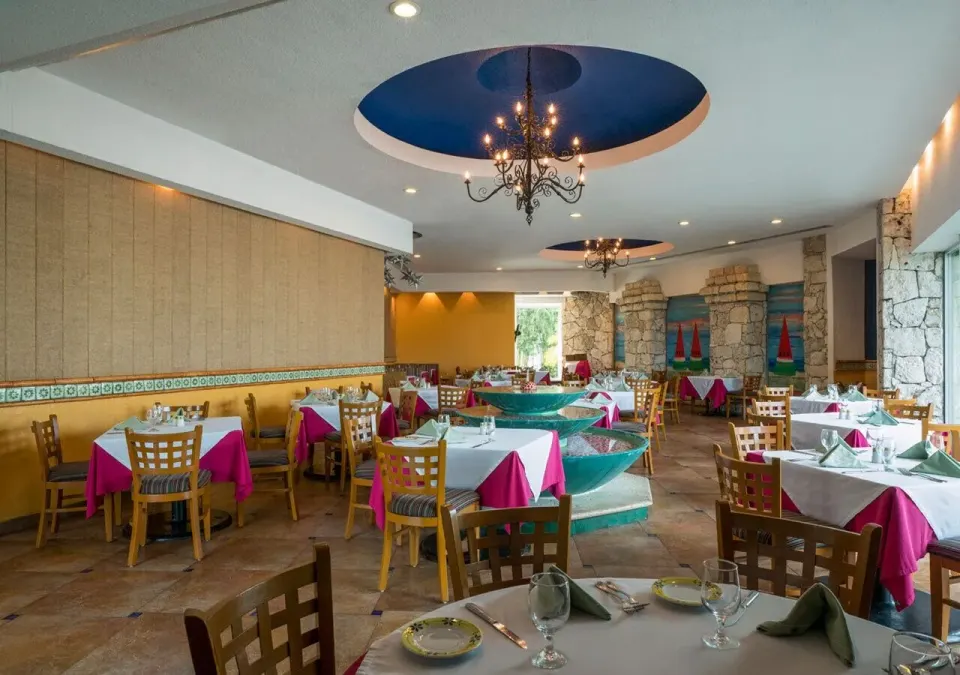 Bright indoor restaurant dining room with colorful table linens at Grand Park Royal Cozumel