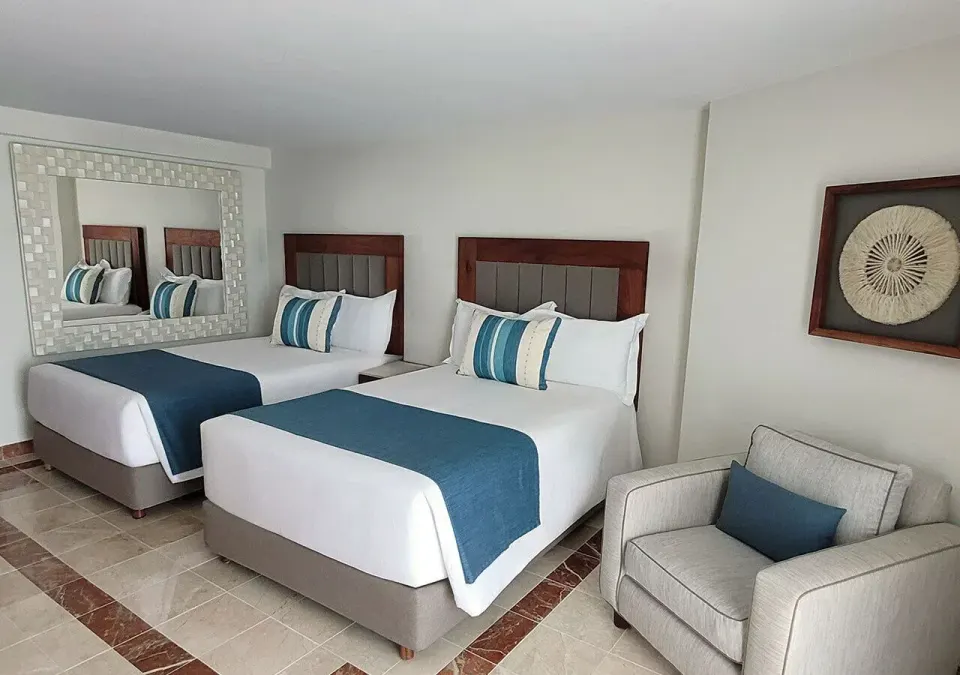 Two beds and an armchair in a deluxe guest room at Grand Park Royal Cozumel