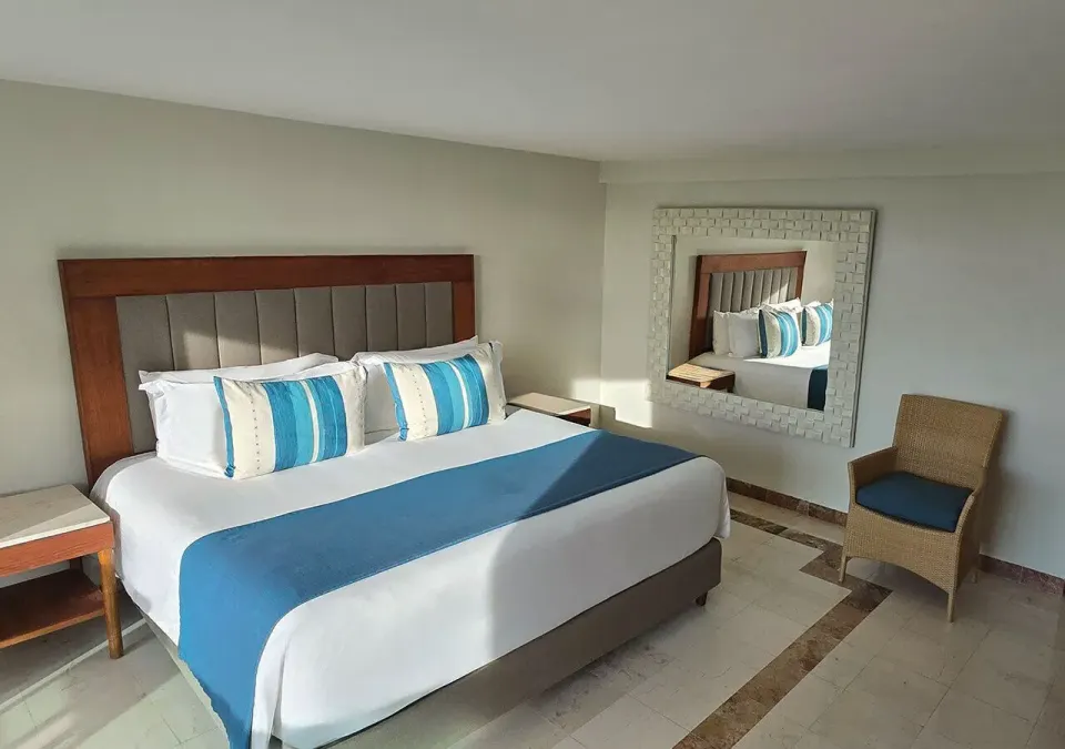 Well-lit king bed with decorative pillows and mirror in Deluxe High Floor King at Grand Park Royal Cozumel