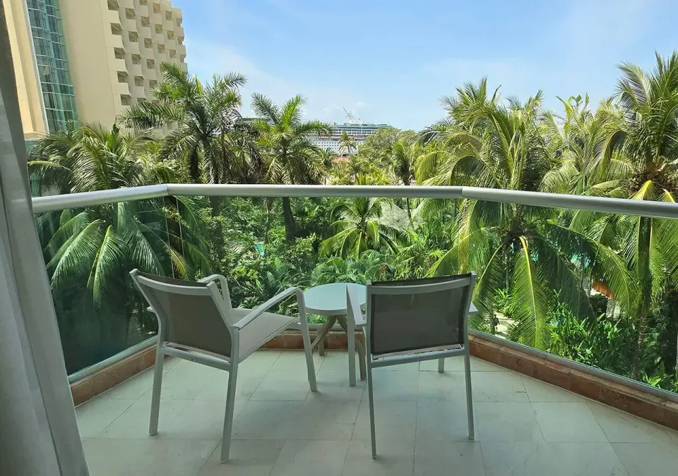 Balcony chairs and table overlooking palm trees from Deluxe Nature View King at Grand Park Royal Cozumel