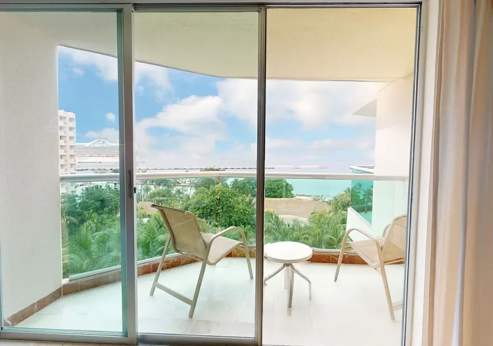 Balcony with chairs and partial ocean view from a Deluxe Superior room at Grand Park Royal Cozumel