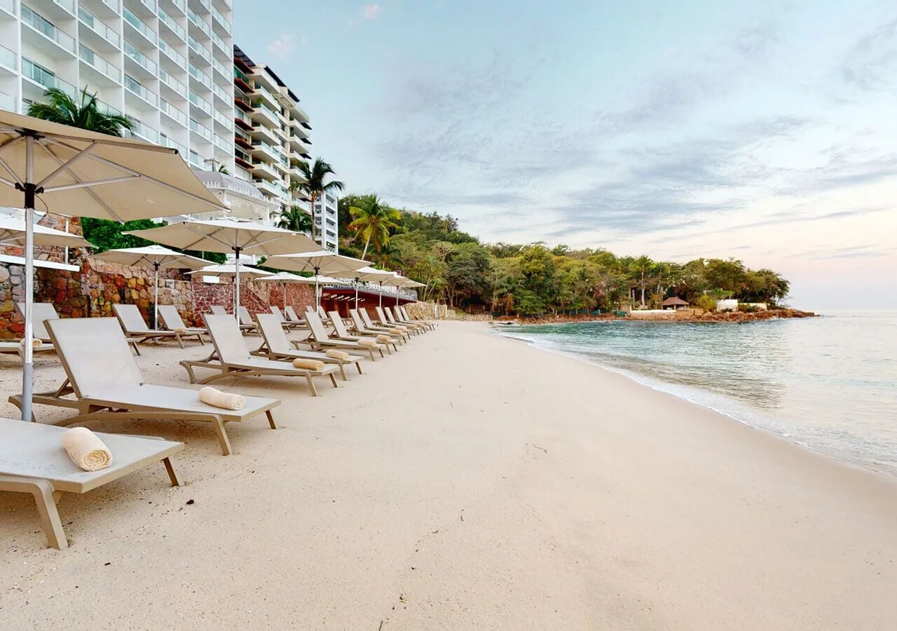 Beach loungers and umbrellas line the sand at Grand Park Royal Puerto Vallarta.