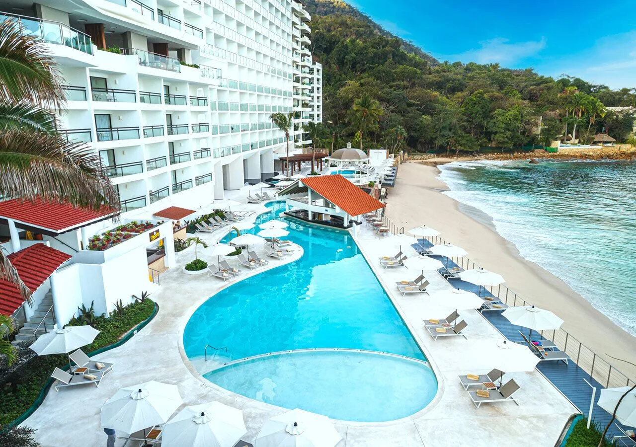 Beachfront pool, lounge chairs and hotel tower at Grand Park Royal Puerto Vallarta.
