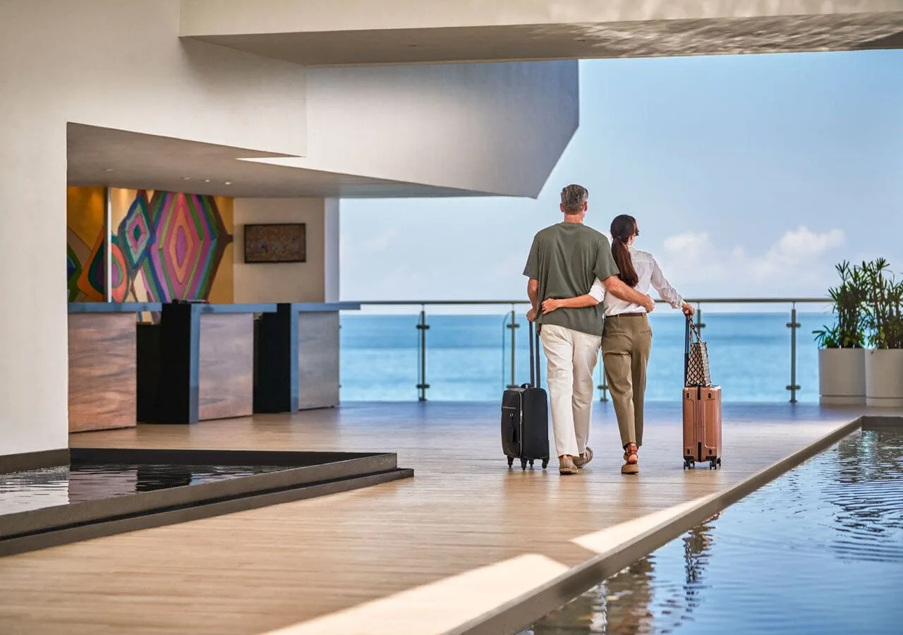 Guests with suitcases walk through the ocean-view lobby at Grand Park Royal Puerto Vallarta.