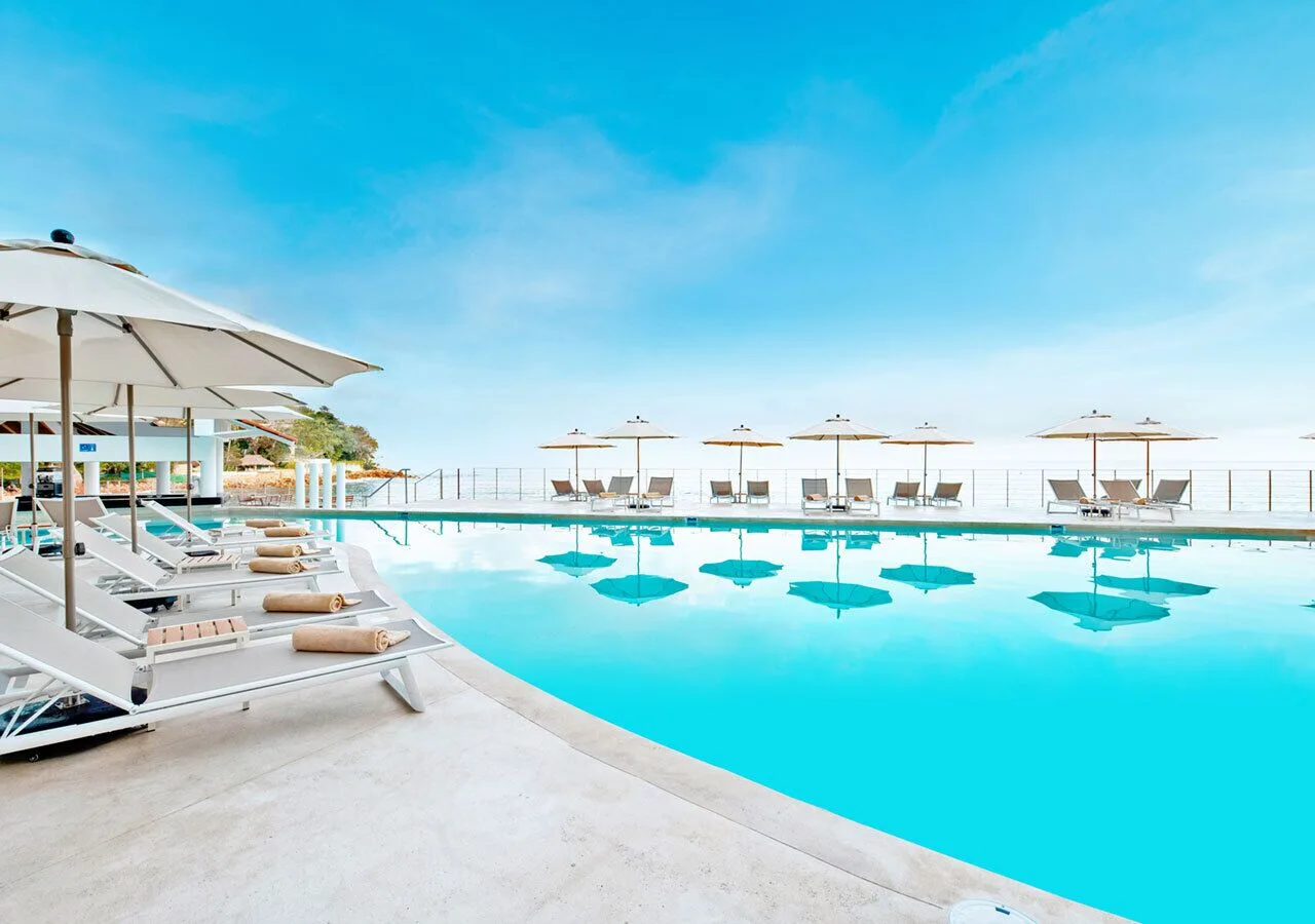 Infinity-style pool with loungers and umbrellas at Grand Park Royal Puerto Vallarta.