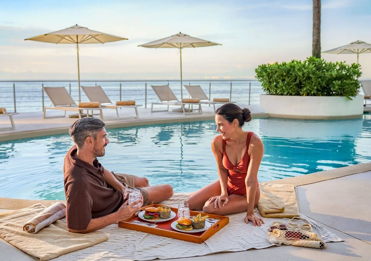 Couple enjoying poolside food beside the ocean at Grand Park Royal Puerto Vallarta.