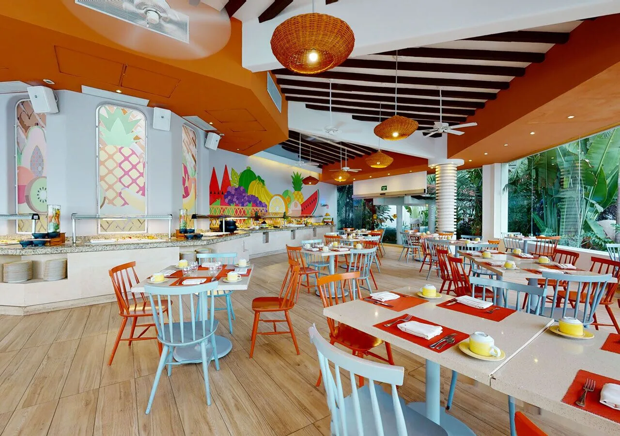 Open restaurant with buffet stations and orange accents at Grand Park Royal Puerto Vallarta.