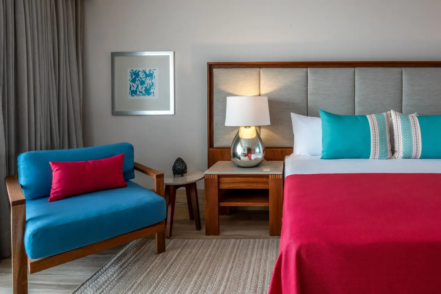 Deluxe room bed and blue lounge chair at Grand Park Royal Puerto Vallarta.