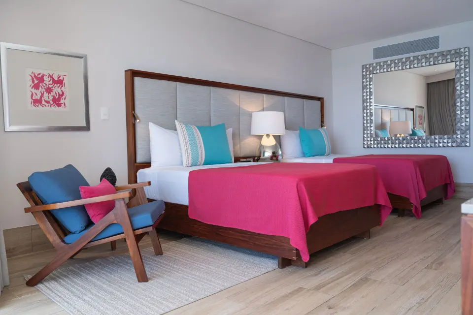 Deluxe room with two beds and a blue chair at Grand Park Royal Puerto Vallarta.