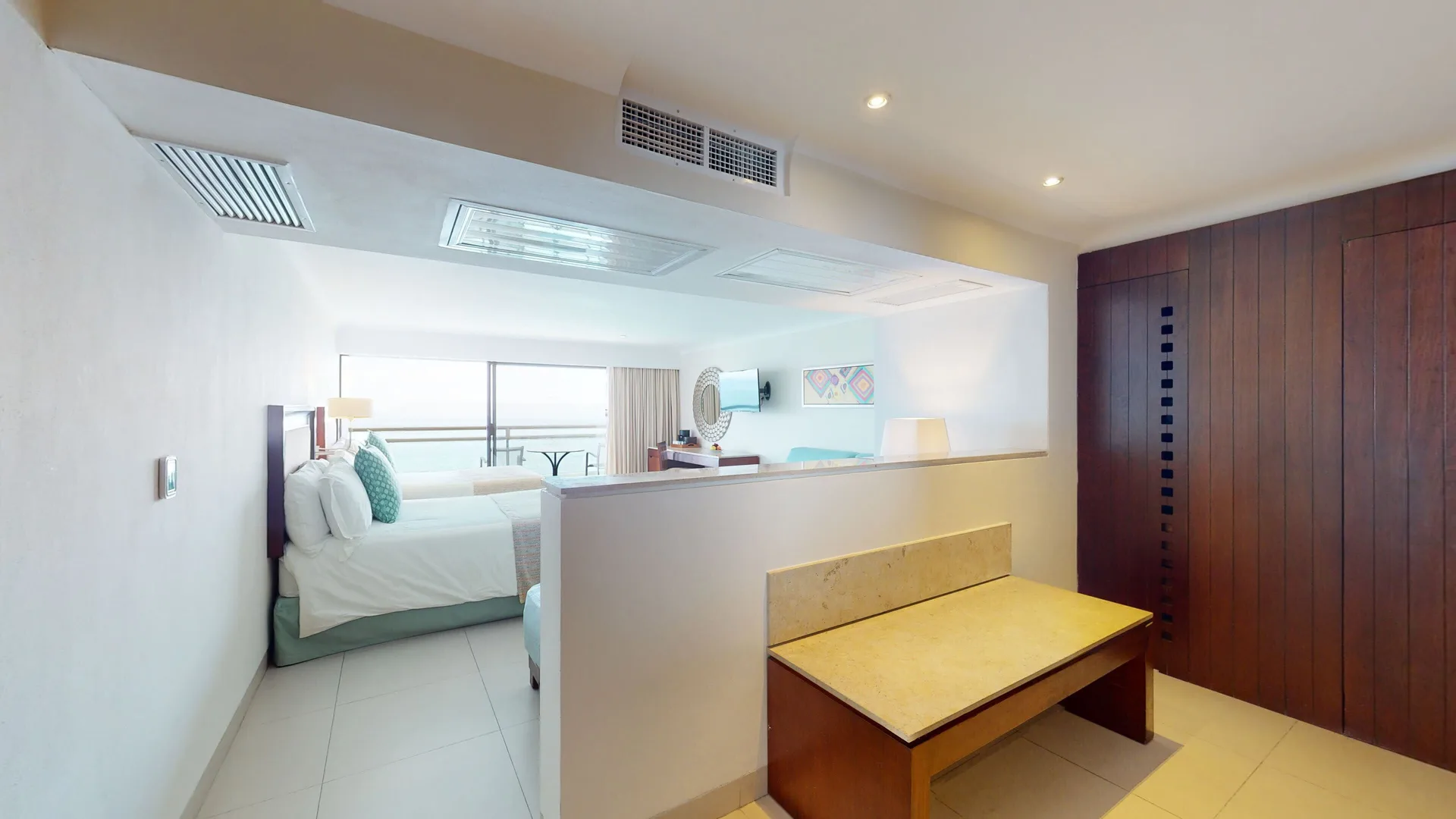 Family Suite entry with bench, bedroom, and balcony beyond at Grand Park Royal Puerto Vallarta.