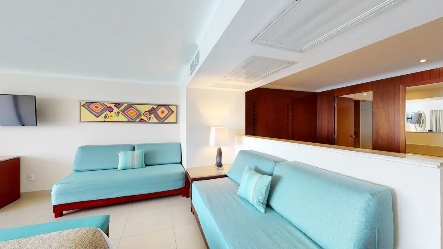 Family Suite sitting area with aqua sofas and wall art at Grand Park Royal Puerto Vallarta.
