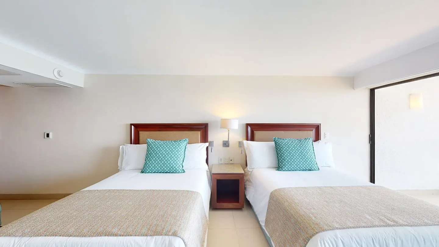 Junior Suite with two beds and bedside lamp at Grand Park Royal Puerto Vallarta.