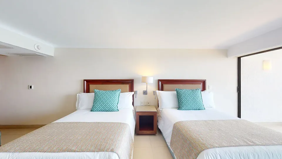 Junior Suite with two beds and bedside lamp at Grand Park Royal Puerto Vallarta.