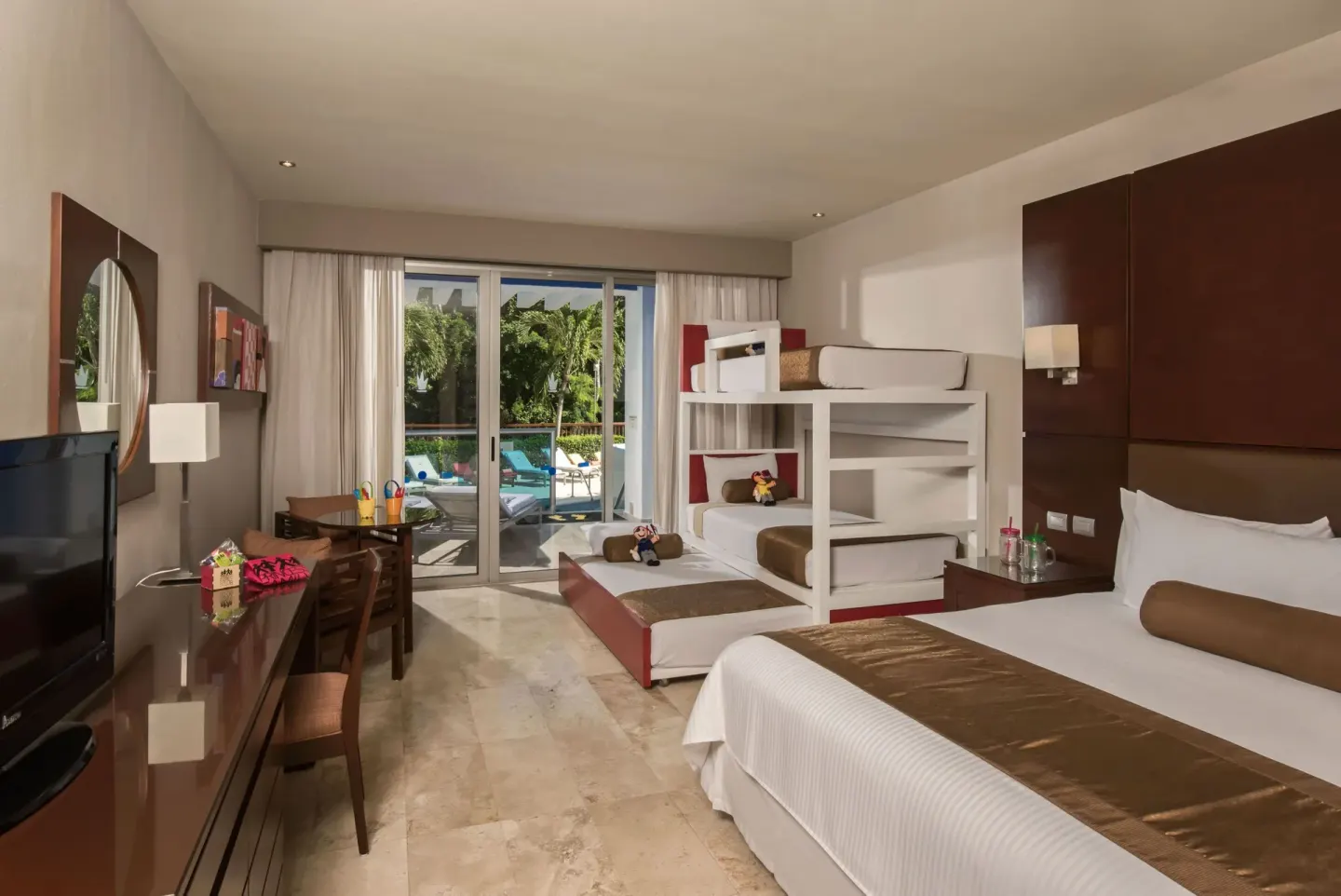 Family guest room with king bed, bunk beds, desk, and patio doors at Grand Riviera Princess.