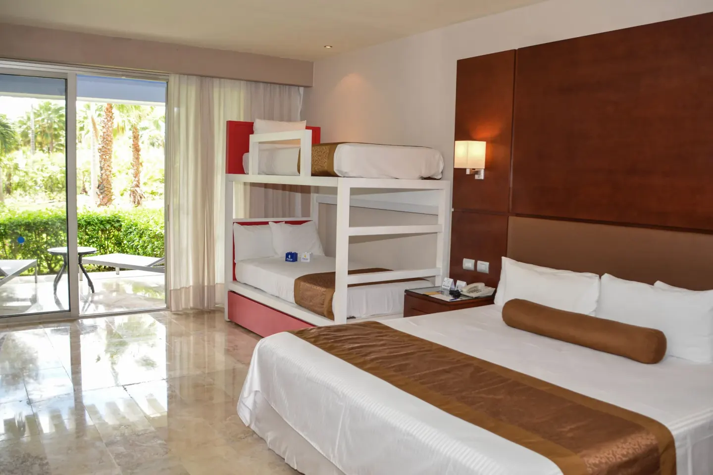 Guest room with king bed, bunk beds, and garden-facing patio doors at Grand Riviera Princess.