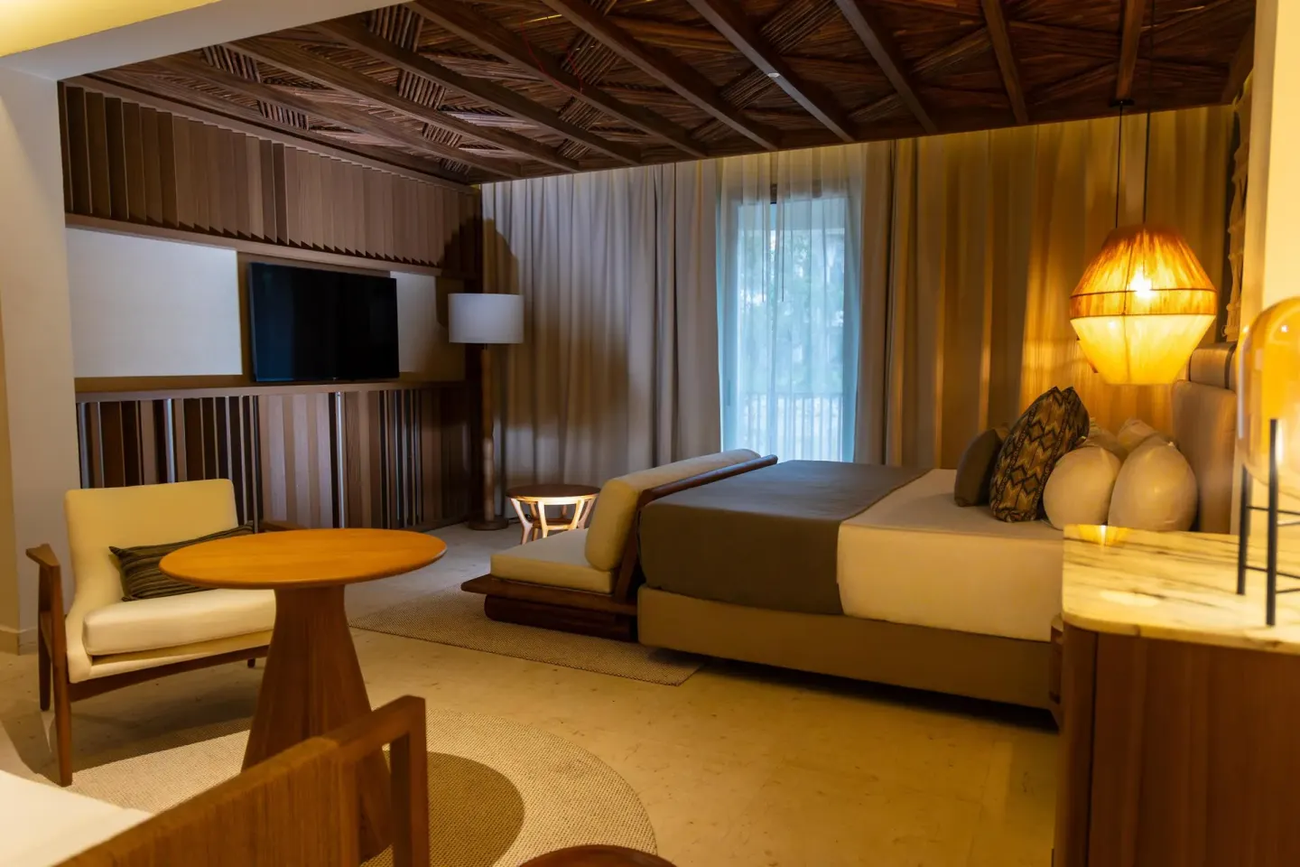 Warm guest room with king bed, seating area, and balcony curtains at Grand Riviera Princess.