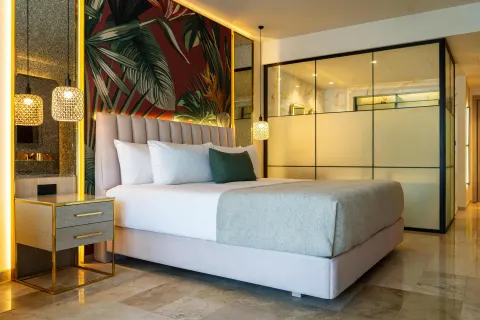 Guest room king bed with tropical mural and glass bathroom wall at Grand Riviera Princess.
