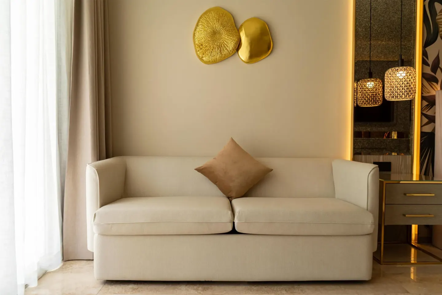 Guest room white sofa with gold wall decor and bedside lamps at Grand Riviera Princess.