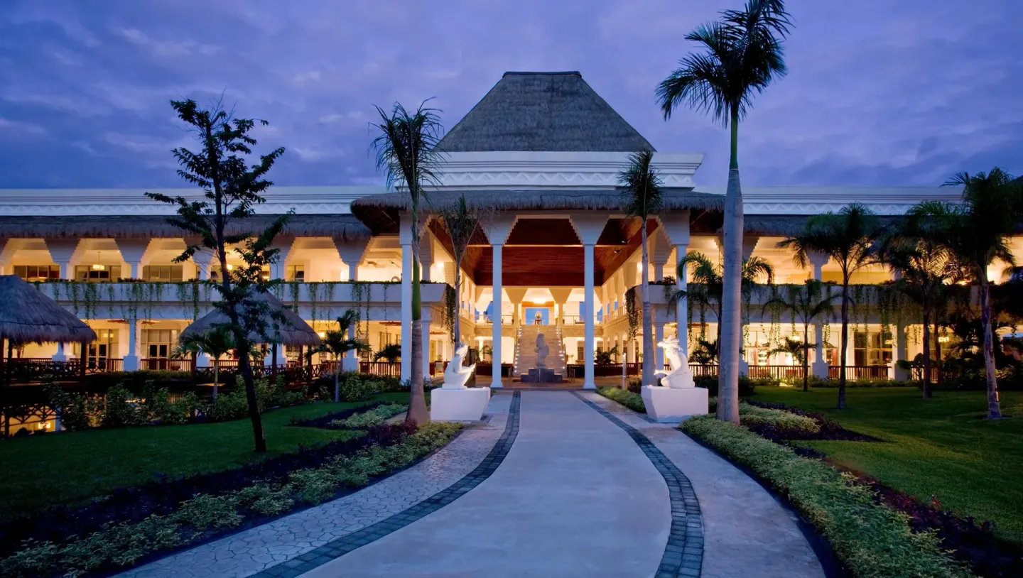 Illuminated resort building and garden walkway at dusk at Grand Riviera Princess.