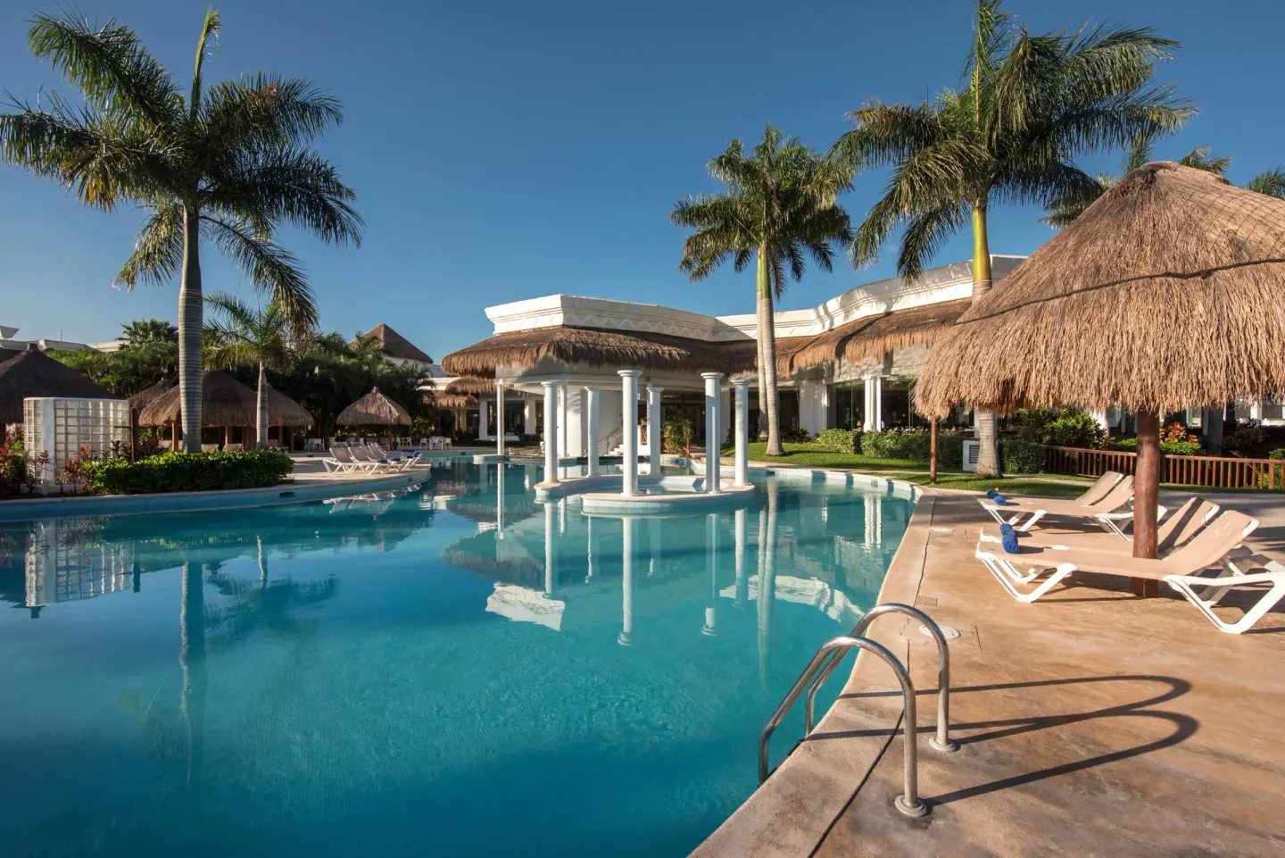 Outdoor pool with palms, loungers and palapa shade at Grand Riviera Princess.