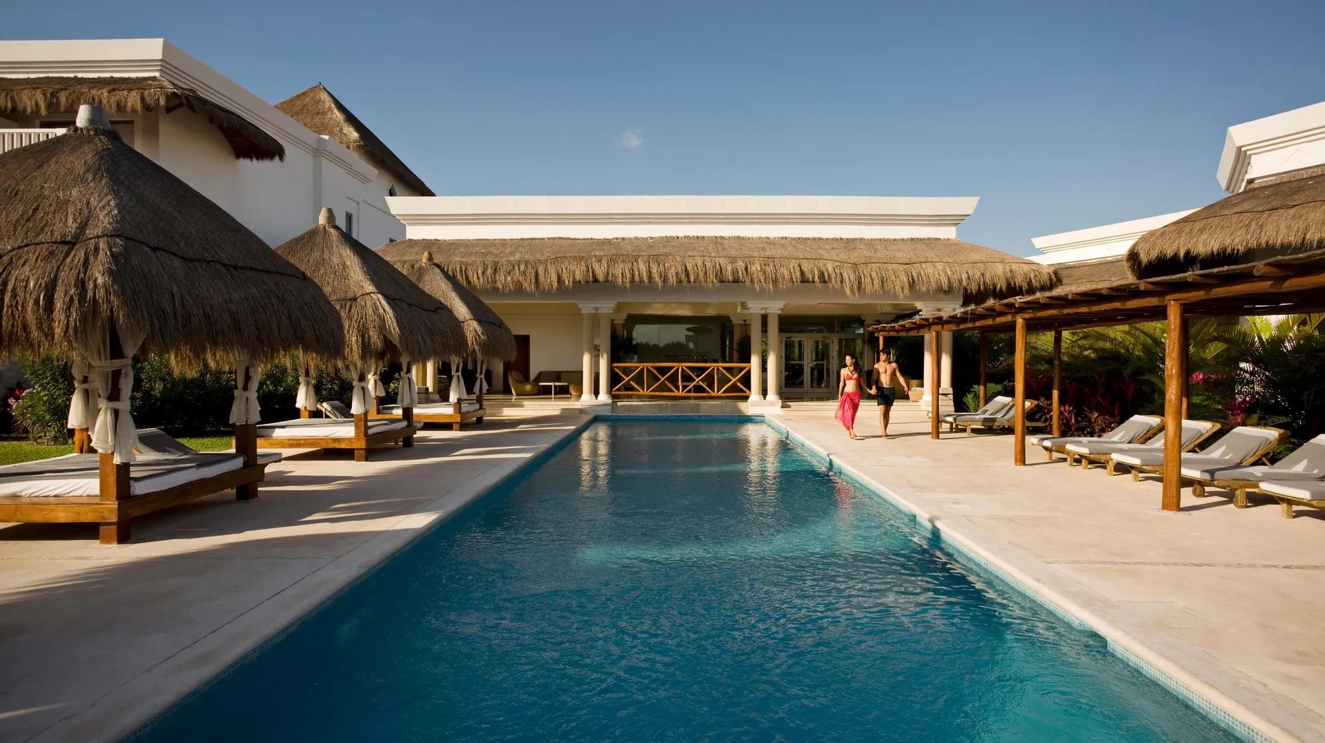Narrow pool with thatched cabanas and loungers at Grand Riviera Princess.