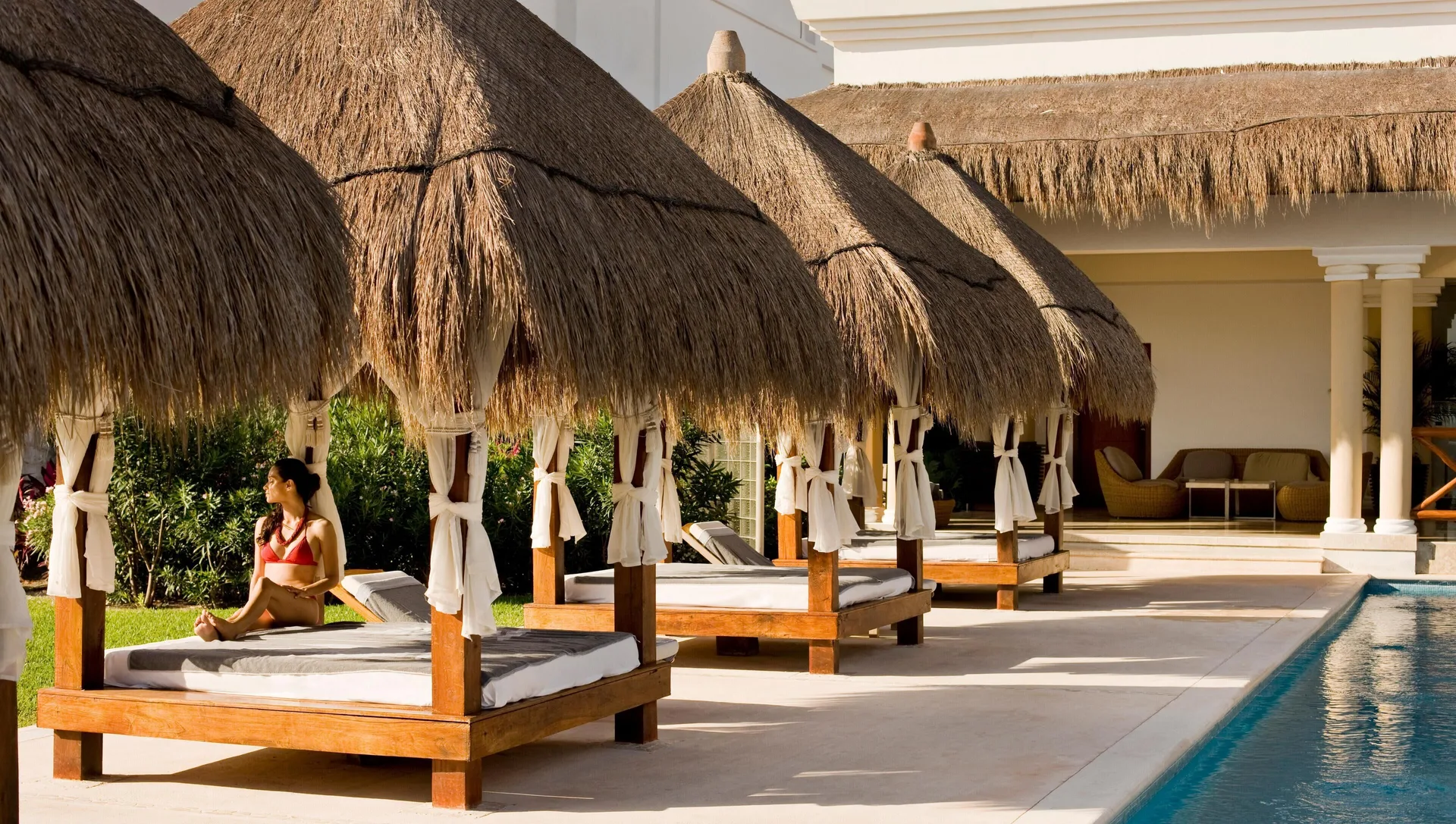 Thatched poolside daybeds beside the water at Grand Riviera Princess.