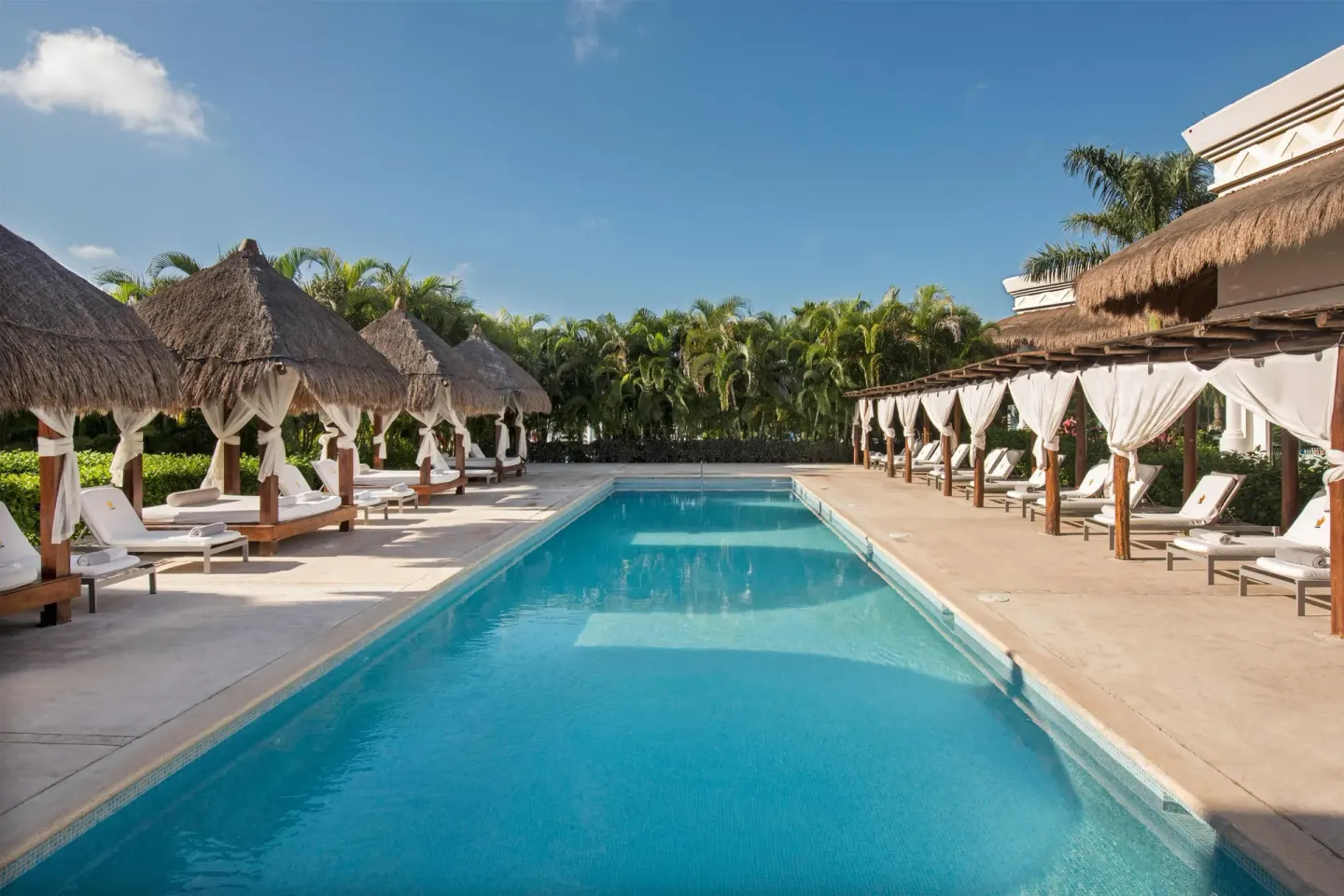 A rectangular pool is framed by thatched cabanas at Grand Riviera Princess.