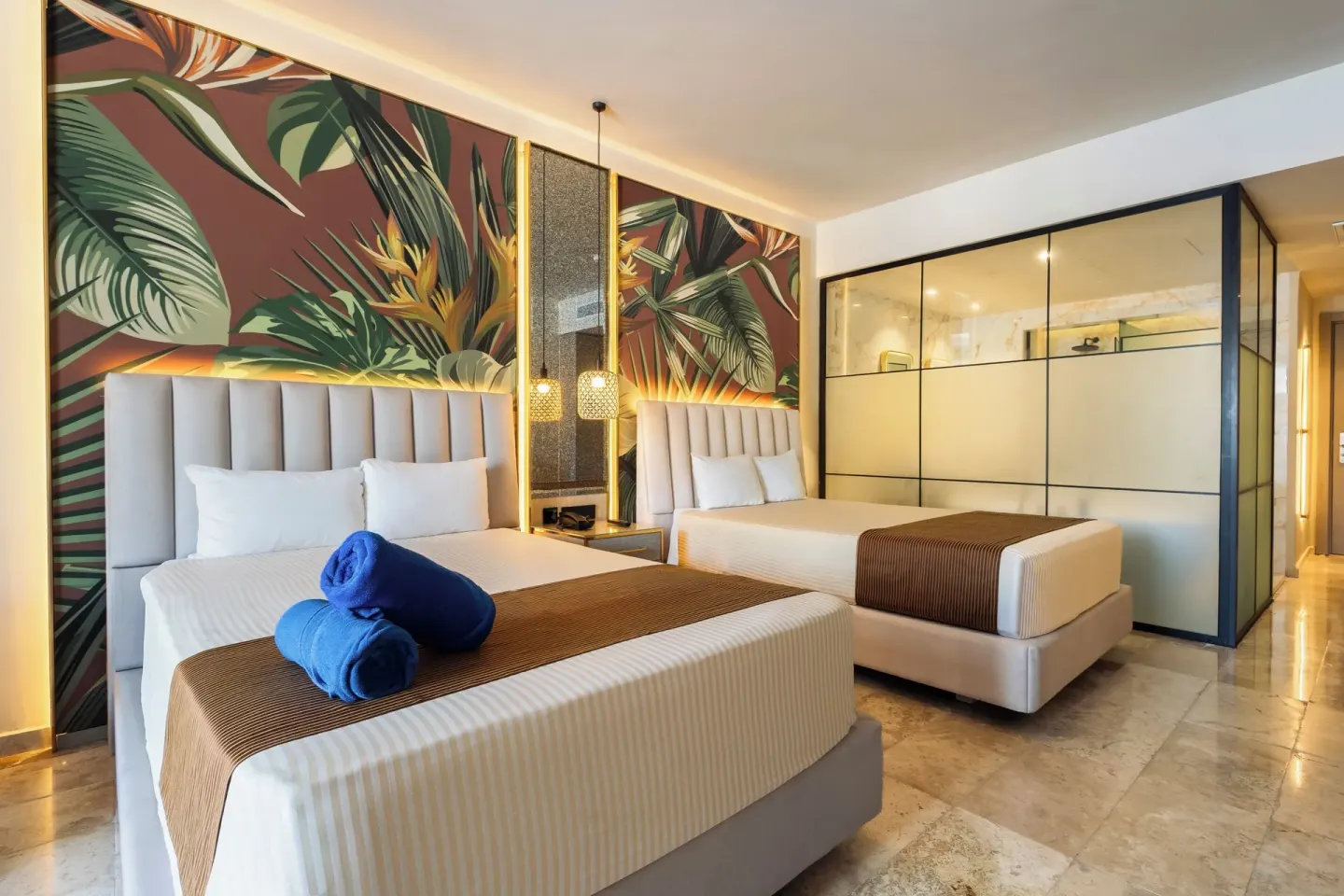 Deluxe Room Garden View with two beds, blue towels, and glass bathroom wall at Grand Riviera Princess.
