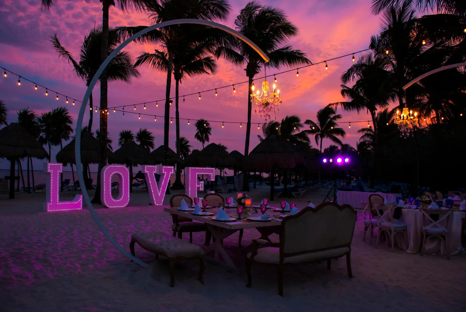 Beach dinner setup with lighted LOVE letters at sunset at Grand Riviera Princess.