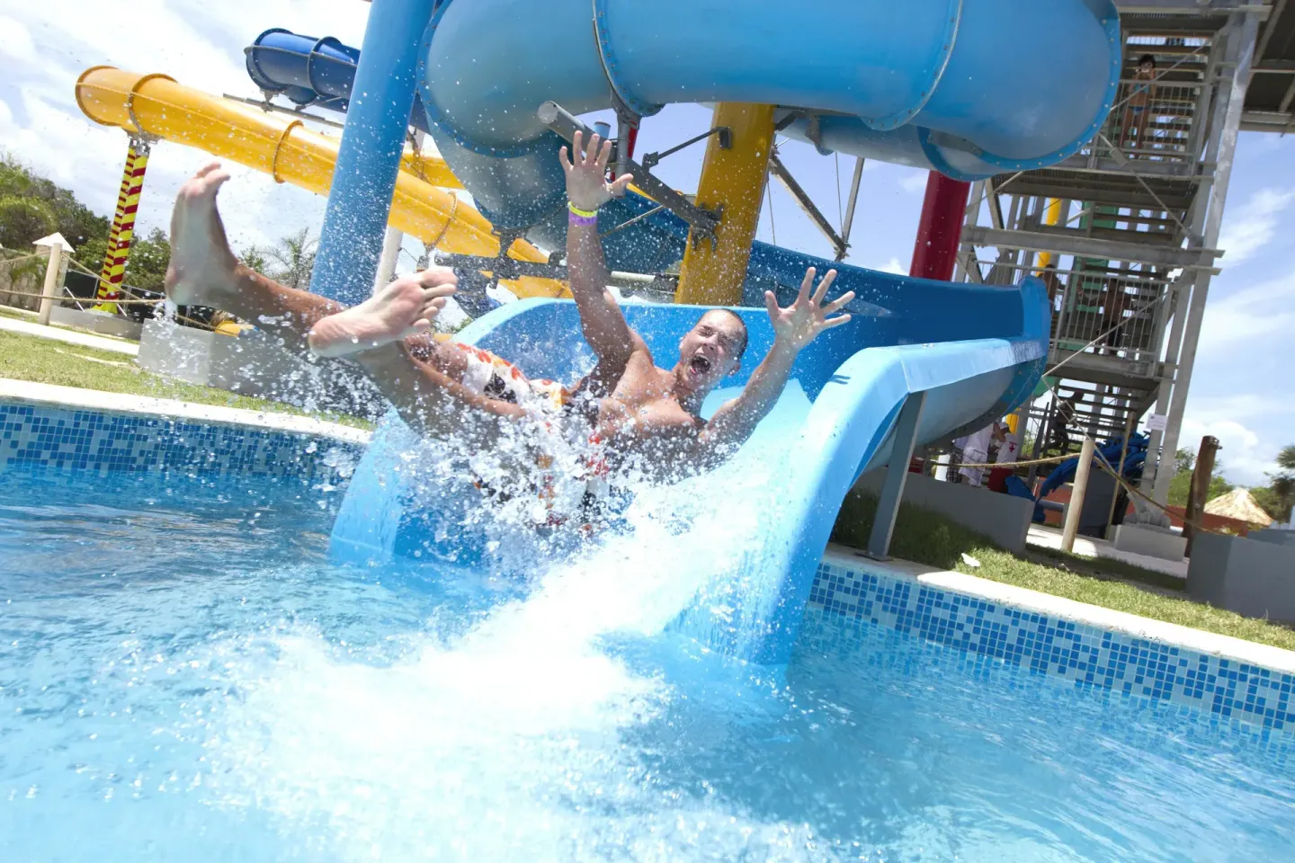 Guest splashing down a blue water slide at Grand Sirenis Punta Cana Resort & Aquagames.