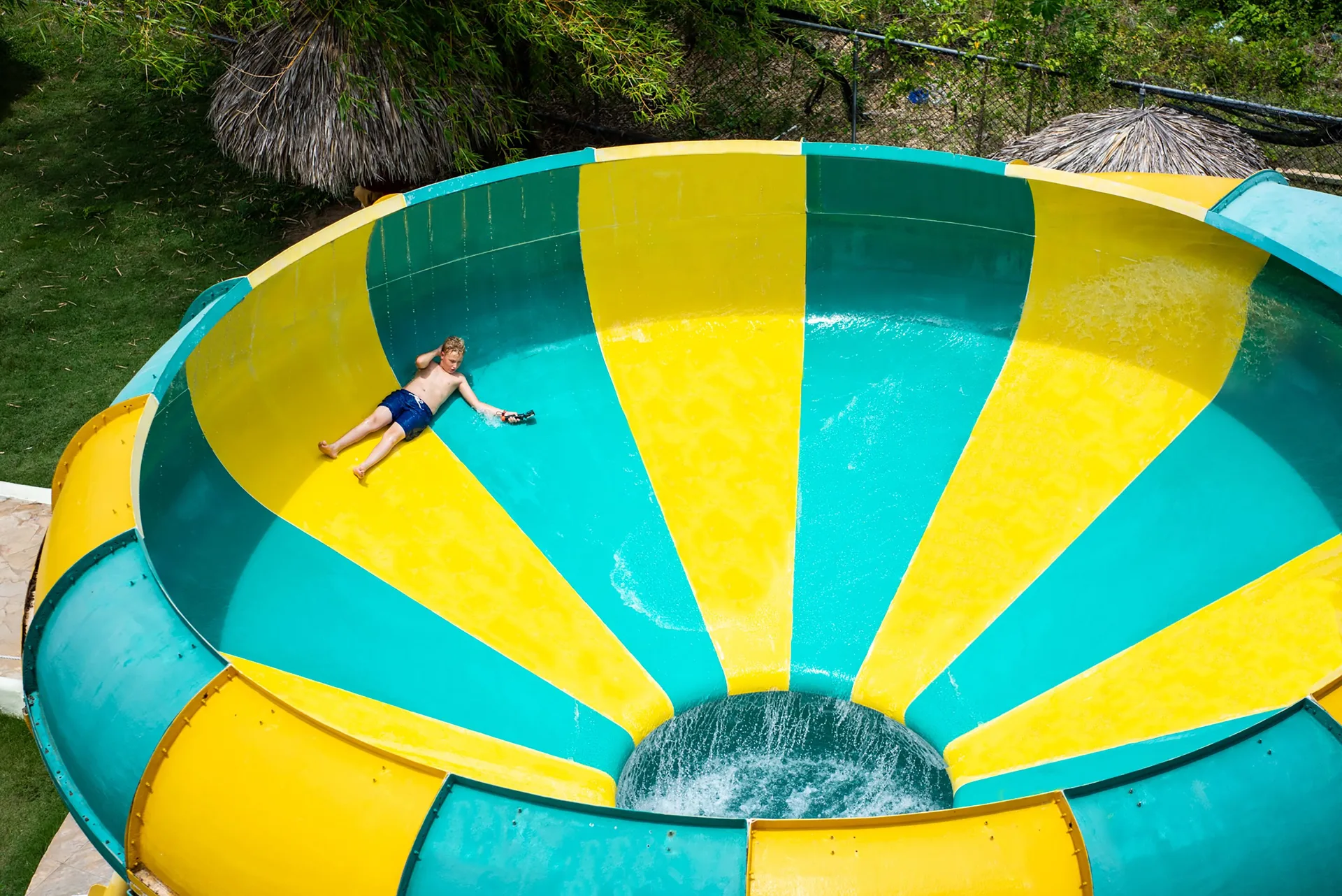 Guest on a yellow and turquoise bowl slide at Grand Sirenis Punta Cana Resort & Aquagames.