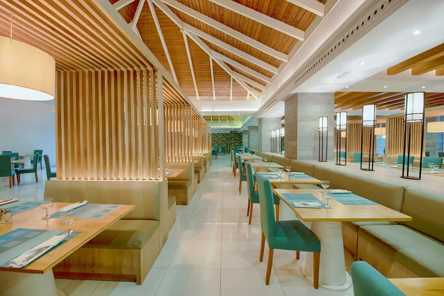 Long restaurant aisle with booths and teal chairs at Grand Sirenis Punta Cana Resort & Aquagames.
